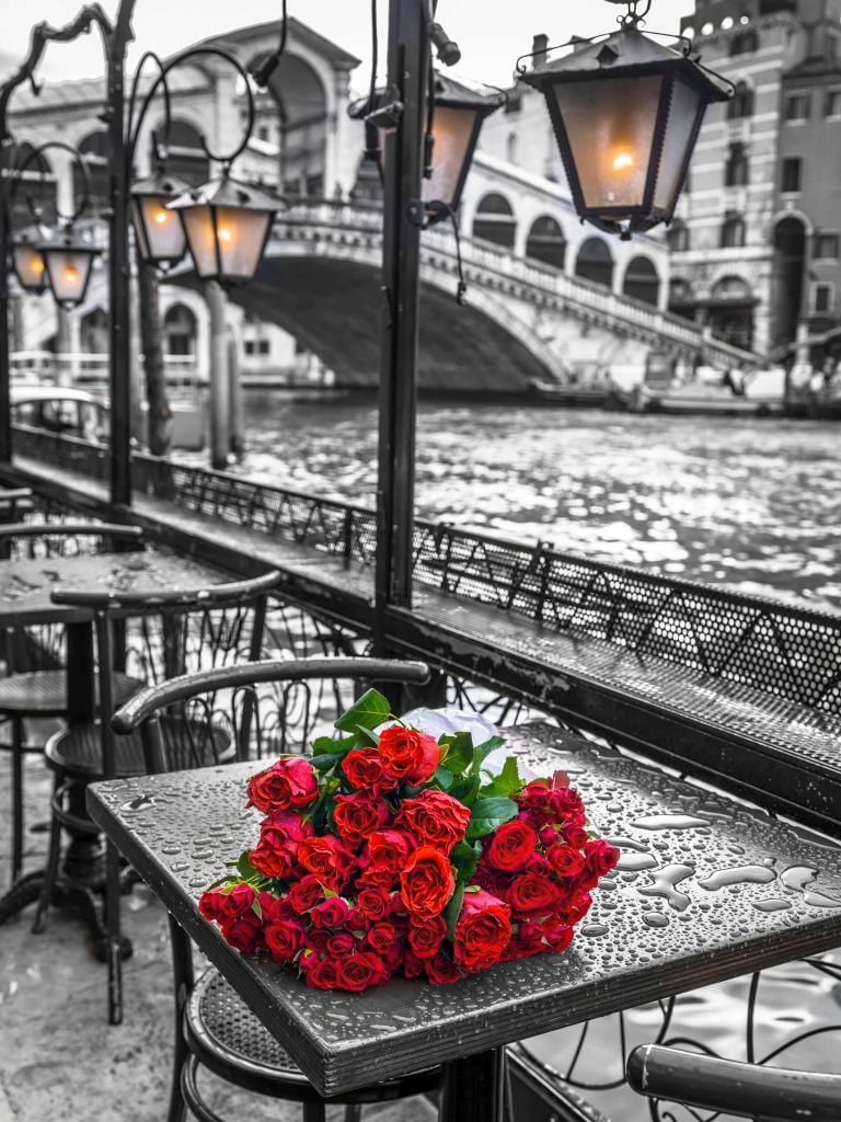 Bunch of red roses on street cafe table, Rialto Bridge, Venice, Italy