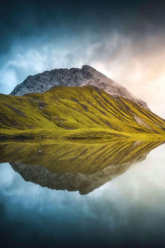 Bjergtop spejles i morgenlys.
