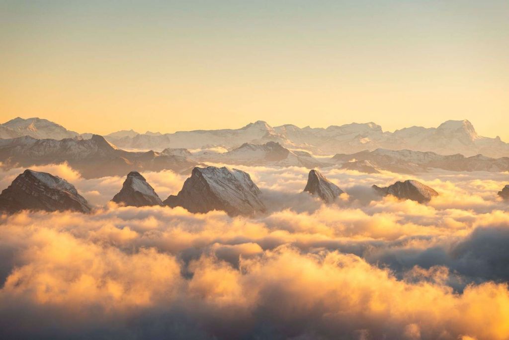 Bergtoppen over gylden skyhav.