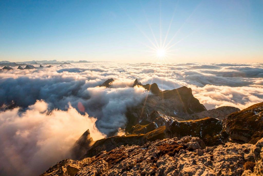 Sonen over skydekket og fjelltoppene