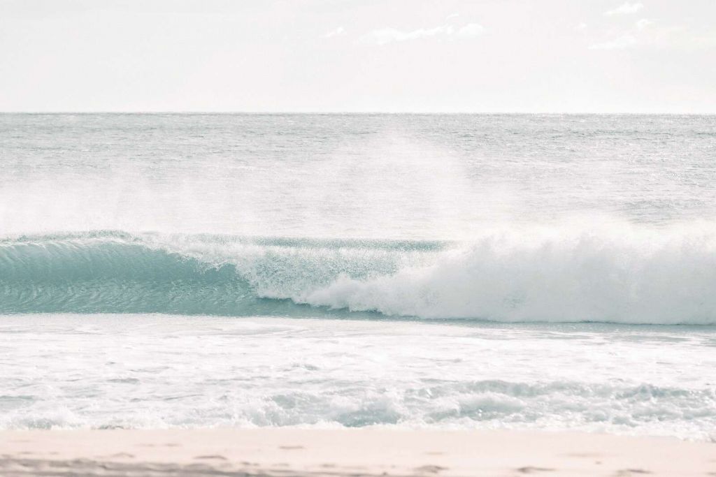 Brydende bølge på klart strand.