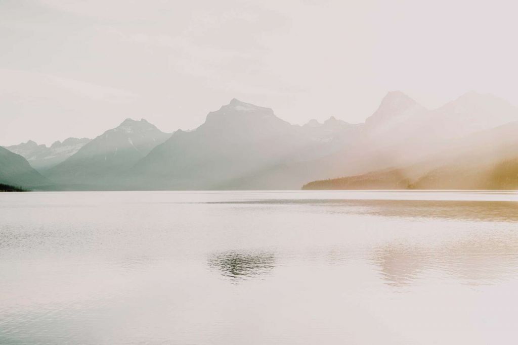 Tågede bjerge over stille sø