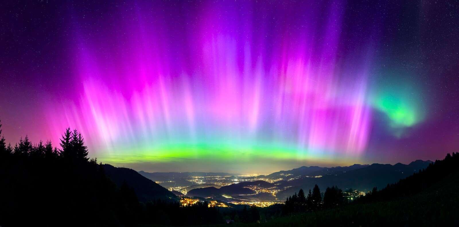 Nordlys over opplyst fjellby