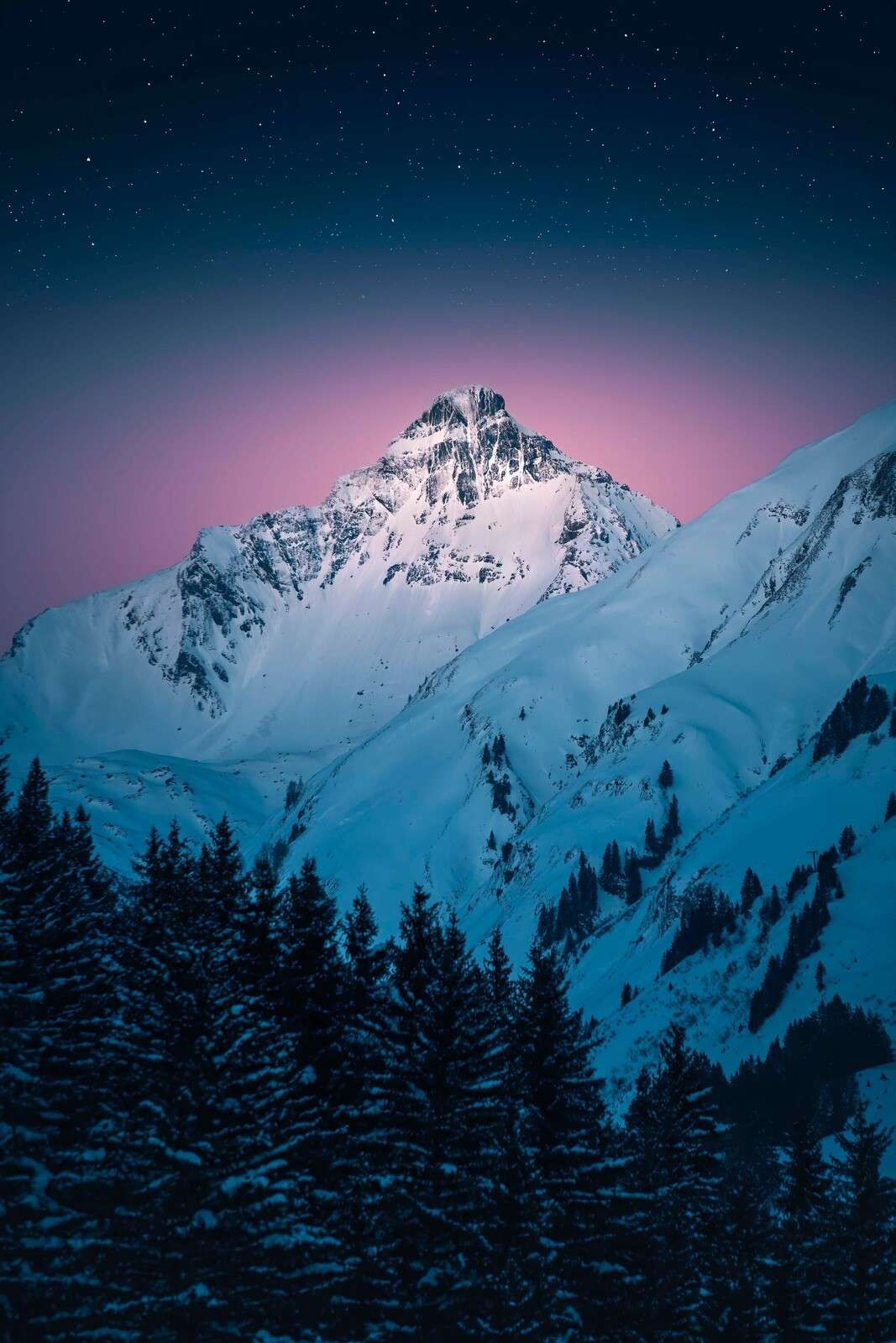 Snødekt fjelltopp under stjernenatt.