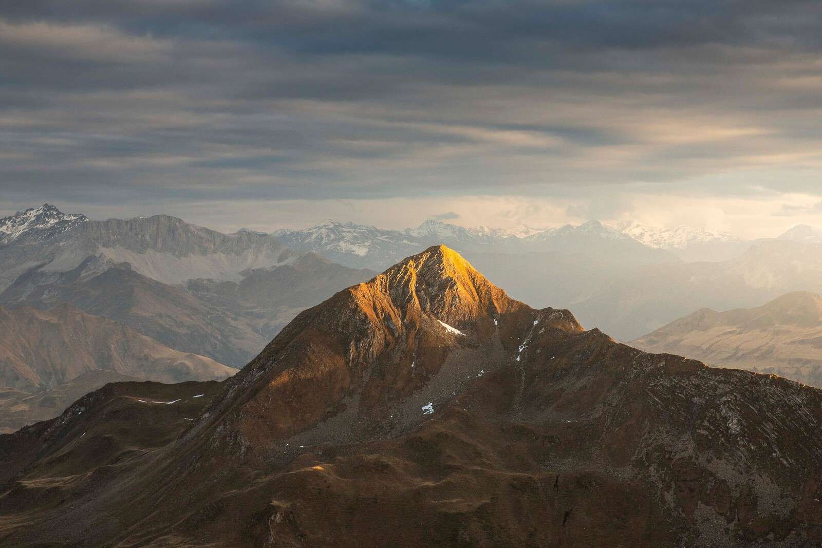 Gyldent sollys på bjergtop ved solopgang.