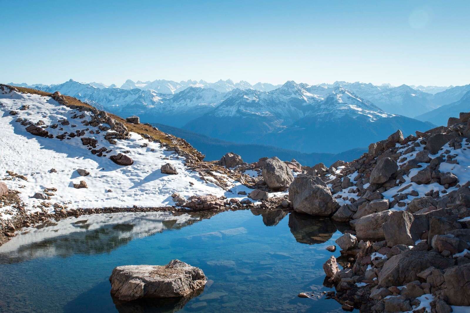 Fjellvann mellom snødekte topper