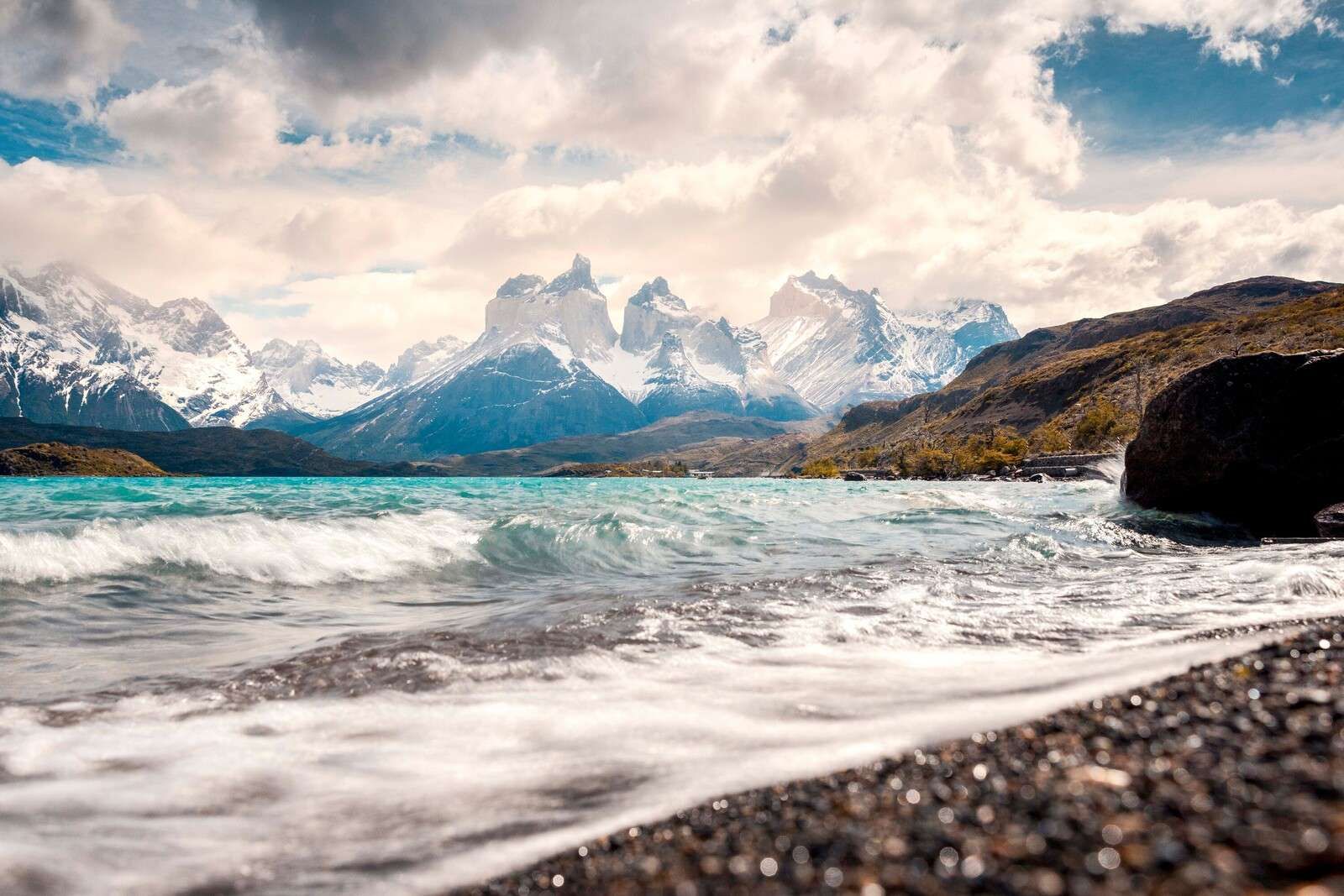 Turkist bergsjø med bølgende kyst.